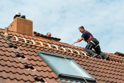 Arbeiten an einer geöffneten Ziegelreihe auf dem Dach.