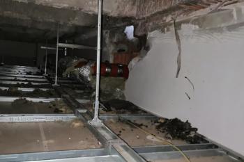 Hohlraum über einer Zwischendecke mit Leitungen und Ablagerungen.
